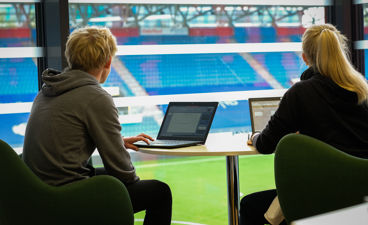 en person og en person som sitter ved et bord med en bærbar datamaskin