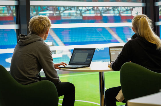 en person og en person som sitter ved et bord med en bærbar datamaskin