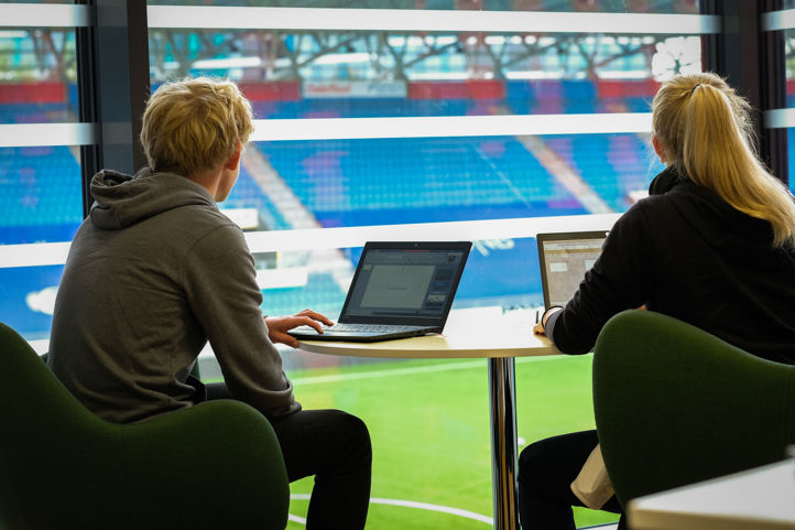 en person og en person som sitter ved et bord med en bærbar datamaskin
